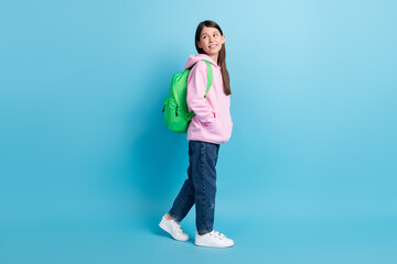 Poster - Full length profile side photo of young girl happy smile rucksack go walk look empty space isolated over blue color background