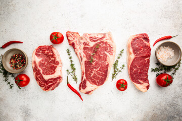 Wall Mural - Variety of Fresh Raw Black Angus Prime Meat Steaks T-bone, New York, Ribeye and seasoning on white background, top view