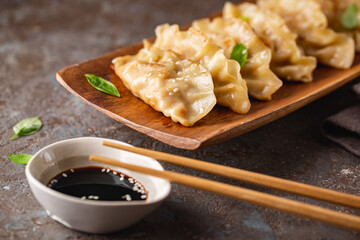 Asian dumplings with soy sauce, sesame seeds and microgreens. Traditional chinese dim sum dumplings on wooden plate.