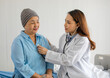 © Bangkok Click Studio - Young and beautiful doctor using stethoscope for diagnosis with Older Asian woman patient covered the head with clothes effect from chemo treatment in cancer cure process