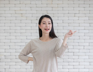 Portrait of cute beautiful mix race Asian adult woman rise hand as in gesture of presenting something with open smile to camera with self-confident and friendly manner.