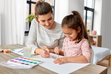family, motherhood and leisure concept - mother spending time with her little daughter with colors p