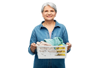 cleaning, wash and old people concept - portrait of smiling senior woman in denim shirt with towels in laundry basket over white background