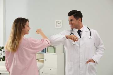 Wall Mural - Doctor and patient doing elbow bump instead of handshake in clinic. New greeting during COVID-19 pandemic