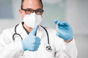 Wall Mural - doctor with medical face mask and medical gloves with a pulled up syringe ready for vaccination shows thumbs up