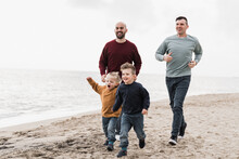 Gay Family Having Fun Together On The Beach In Summer Vacation - LGBT Dads And Sons Lifestyle Concept - Main Focus On Right Man Face