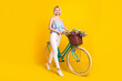 Full body profile photo of positive blond hair lady ride bicycle wear top pants isolated on yellow background