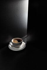 White cup with black coffee on a black table