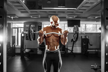 Wall Mural - Muscular man working out in gym doing exercises with dumbbells at biceps, strong male naked torso abs