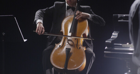 Young man playing double bass against black background