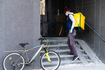 Wall Mural - Delivery Man standing with yellow thermo backpack for food delivery near the entrance home with empty space to copy paste