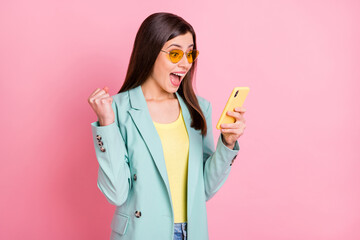 Wall Mural - photo portrait of excited amazed woman celebrating holding phone in one hand isolated on pastel pink