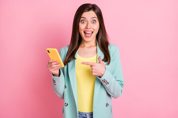 Wall Mural - photo portrait of excited amazed woman pointing finger at holding phone in one hand isolated on past