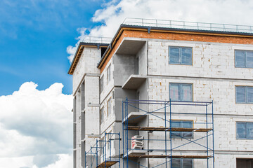 Facade white cilicate blocks material of a new modern urban unfinished house at a construction site against a blue sky with clouds