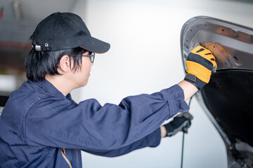 Wall Mural - Asian auto mechanic opening bonnet hood checking car engine in auto service garage. Mechanical maintenance engineer working in automotive industry. Automobile servicing and repair