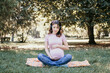 © Anna - Young pregnant woman listening to music in the park on a spring or summer day. Place for text.