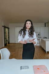 Wall Mural - Confident young brunette woman holding documents near the desk