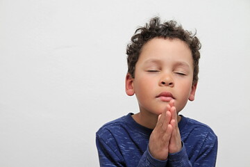 boy praying to God with hands together on white background stock photo