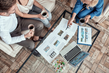 Wall Mural - Top view of female travel agent working with clients in office and offering them tours