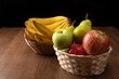 tropical fruit basket in detail on wooden surface, black background, selective focus.