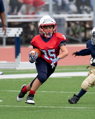 Wall Mural - Young athletic boy playing in a youth tackle football game