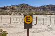 © David - Yellow, wooden parking sign in Spanish (Estacionamiento) in an empty, arid nature reserve with hills on the background
