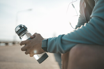 Wall Mural - sport man sitting after running and holding water bottle drink. Sport thirsty and resting after exercise.