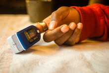 Closeup shot of a pulse oximeter on a black woman's finger to measure pulse rate and oxygen levels