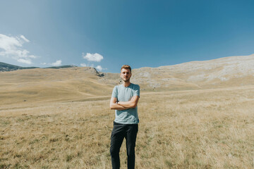 Wall Mural - Handsome bearded Caucasian man standing on a meadow