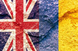 Closeup shot of UK and Ukraine flags together isolated on rock wall background