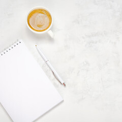 Wall Mural - Cup of coffee, open notebook and pen on a light concrete background. Workplace top view