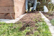 Ein Mann verlegt Kabel für Rasenroboter im Garten.
