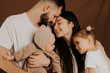 © Ananass - A young sincere family where a stylish bearded father and a cute wife hold their cute children in their arms. Family photo shoot in the studio