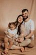 © Ananass - A young sincere family where a stylish bearded father and a cute wife hold their cute children in their arms. Family photo shoot in the studio