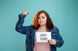 © golubovy - Hard work note. Protest campaign. Female struggle. Gender discrimination. Conceptual portrait. Confident plus size woman holding paper with inscription threatening by fist isolated blue.