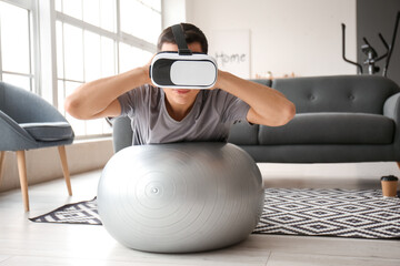 Wall Mural - Sporty young man with virtual reality glasses training at home