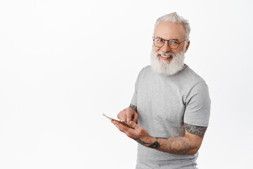 Happy smiling grandfather in glasses using digital tablet, shopping online, standing in gray t-shirt against white background