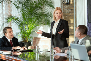 Poster - A person speaking to colleagues at working meeting in boardroom