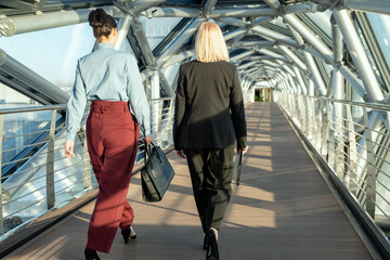 Wall Mural - rear view of contemporary businesswomen walking along modern building