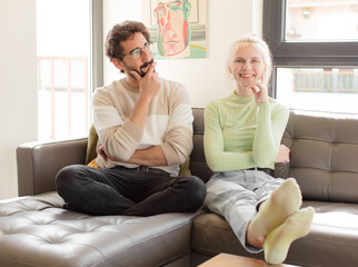 Wall Mural - young couple young couple smiling happily and daydreaming or doubting, looking to the side