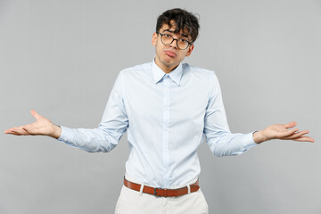 Young confused mistaken employee business latin man corporate lawyer in classic white shirt glasses spread hands oops gesture isolated on grey background studio portrait Career achievement concept