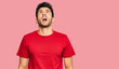 © Krakenimages.com - Young handsome man wearing casual red tshirt angry and mad screaming frustrated and furious, shouting with anger. rage and aggressive concept.
