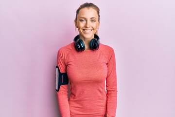 Canvas Print - Beautiful caucasian woman wearing sportswear and arm band with a happy and cool smile on face. lucky person.