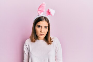 Poster - Young beautiful woman wearing cute easter bunny ears relaxed with serious expression on face. simple and natural looking at the camera.