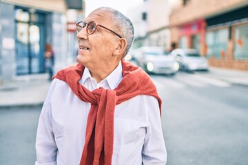 Wall Mural - senior man smiling happy wearing glasses walking at the city.