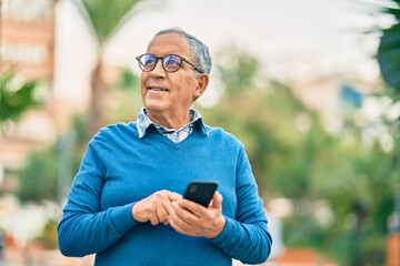 Wall Mural - senior grey-haired man smiling happy using smartphone at the city.
