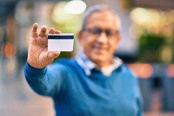 Wall Mural - senior grey-haired man smiling happy holding credit card at the city.