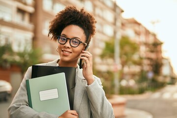 Poster - Young african american businesswoman smiling happy talking on the smartphone at the city.