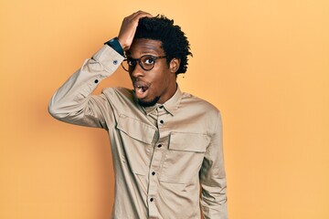 Sticker - Young african american man wearing casual clothes and glasses surprised with hand on head for mistake, remember error. forgot, bad memory concept.