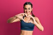 Young brunette girl wearing sportswear and braids smiling in love doing heart symbol shape with hands. romantic concept.
